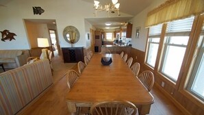 A spacious dining area with a long wooden table and multiple chairs, a sofa, and a fireplace. - KD904- Semi-OF favorite with elevator, 4 master suites and gourmet kitchen!! (Kill Devil Hills)