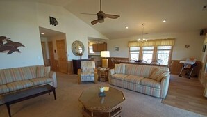 A spacious living room with striped sofas, a coffee table, and a ceiling fan. - KD904- Semi-OF favorite with elevator, 4 master suites and gourmet kitchen!! (Kill Devil Hills)