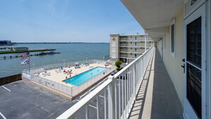 Een balkon met een zwembad, met uitzicht op een wateroppervlak en een pier in de verte.