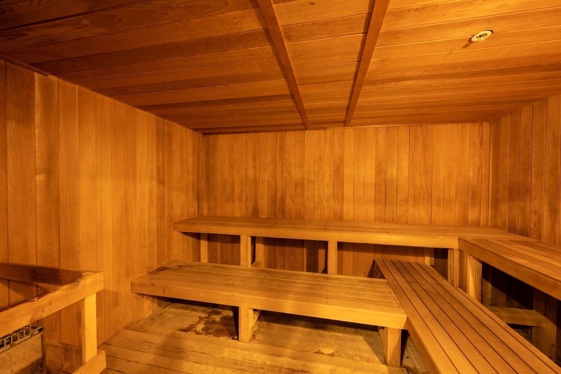 A sauna with wooden benches and a sloped floor.