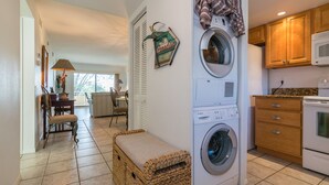 A laundry area with a washing machine, dryer, and wooden cabinets. - Gulfsands 201 · Manatee Beach · Elevator · Pool (Holmes Beach)