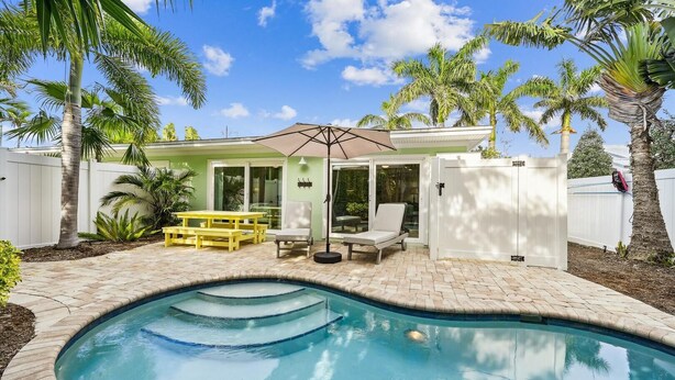 A backyard with a swimming pool, a patio with yellow benches, and a covered seating area. - Ground Floor Two Bedroom Island Styled Home on Beautiful Anna Maria.  Close to Beaches!! (Holmes Beach)