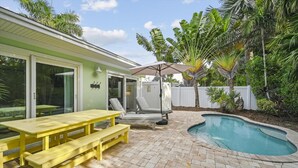 A backyard with a pool, a yellow picnic table, and lounge chairs. - Ground Floor Two Bedroom Island Styled Home on Beautiful Anna Maria.  Close to Beaches!! (Holmes Beach)