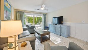 A living room with a sofa, armchair, coffee table, TV, and a view of the outdoors. - Ground Floor Two Bedroom Island Styled Home on Beautiful Anna Maria.  Close to Beaches!! (Holmes Beach)