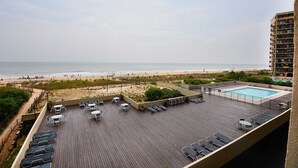 A rooftop pool area with sun loungers and a view of the beach.