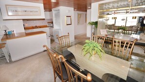 A modern kitchen with a glass dining table, wooden chairs, and a white countertop.