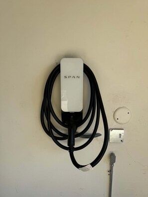 A wall-mounted charging station with a cable and a metal box labeled 'SPAN'.