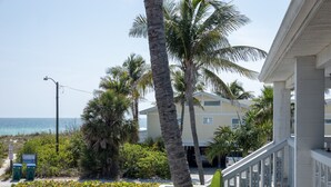 A beachfront property with a white building, palm trees, and a view of the ocean.