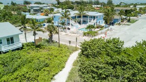 A coastal residential area with a prominent blue house featuring a balcony and a staircase leading to a pool area.