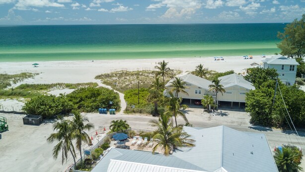 A beachfront property with a large house, a beach, and a clear view of the ocean.