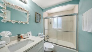 A bathroom with a shower, toilet, sink, and a mirror with decorative elements. - 4BR Coastal Cottage w/ Heated Private Pool | 1 Block to Bean Point Beach | Dog Friendly *(See Note) ! (Anna Maria)