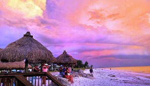 A beach with thatched-roof huts and a wooden walkway.
