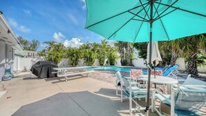 A backyard with a pool, outdoor furniture, and a covered grill area. - 4BR Coastal Cottage w/ Heated Private Pool | 1 Block to Bean Point Beach | Dog Friendly *(See Note) ! (Anna Maria)