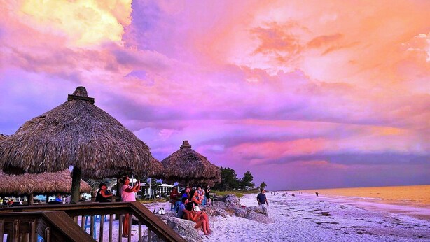 A beach with thatched-roof huts and a wooden walkway. - 4BR Coastal Cottage w/ Heated Private Pool | 1 Block to Bean Point Beach | Dog Friendly  *(See Note) ! (Anna Maria)