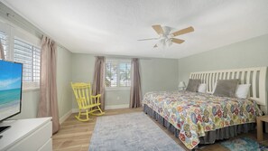 A bedroom with a bed, a chair, a TV, and a ceiling fan. - 4BR Coastal Cottage w/ Heated Private Pool | 1 Block to Bean Point Beach | Dog Friendly  *(See Note) ! (Anna Maria)
