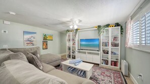 A living room with a sofa, a coffee table, a TV, and bookshelves.