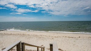 A beach with a wooden railing and a clear view of the ocean.