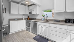A modern kitchen with white cabinetry, stainless steel appliances, and a window providing a view of the outdoors.