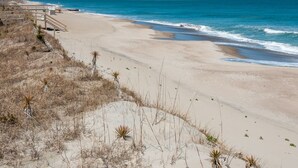 A beach with a wooden walkway leading to a pier. - First floor oceanfront condo in Ocean Dunes! (Kure Beach)