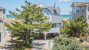 A beachfront property with a large house featuring a covered patio and a view of the ocean. - The Coast Is Clear - Corolla, Ocean Sands, Oceanfront, 150 Ft to Beach, Open All Year, Pets OK (Corolla)