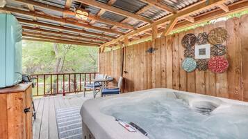 A wooden deck with a hot tub, a table with chairs, and decorative plates on the wall.