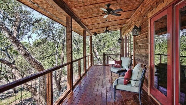 A wooden deck with a railing, two chairs, and a table. - Upscale Luxury Cabin! Has it all Hot tub, Fireplace, Gorgeous Views!!! (Wimberley)