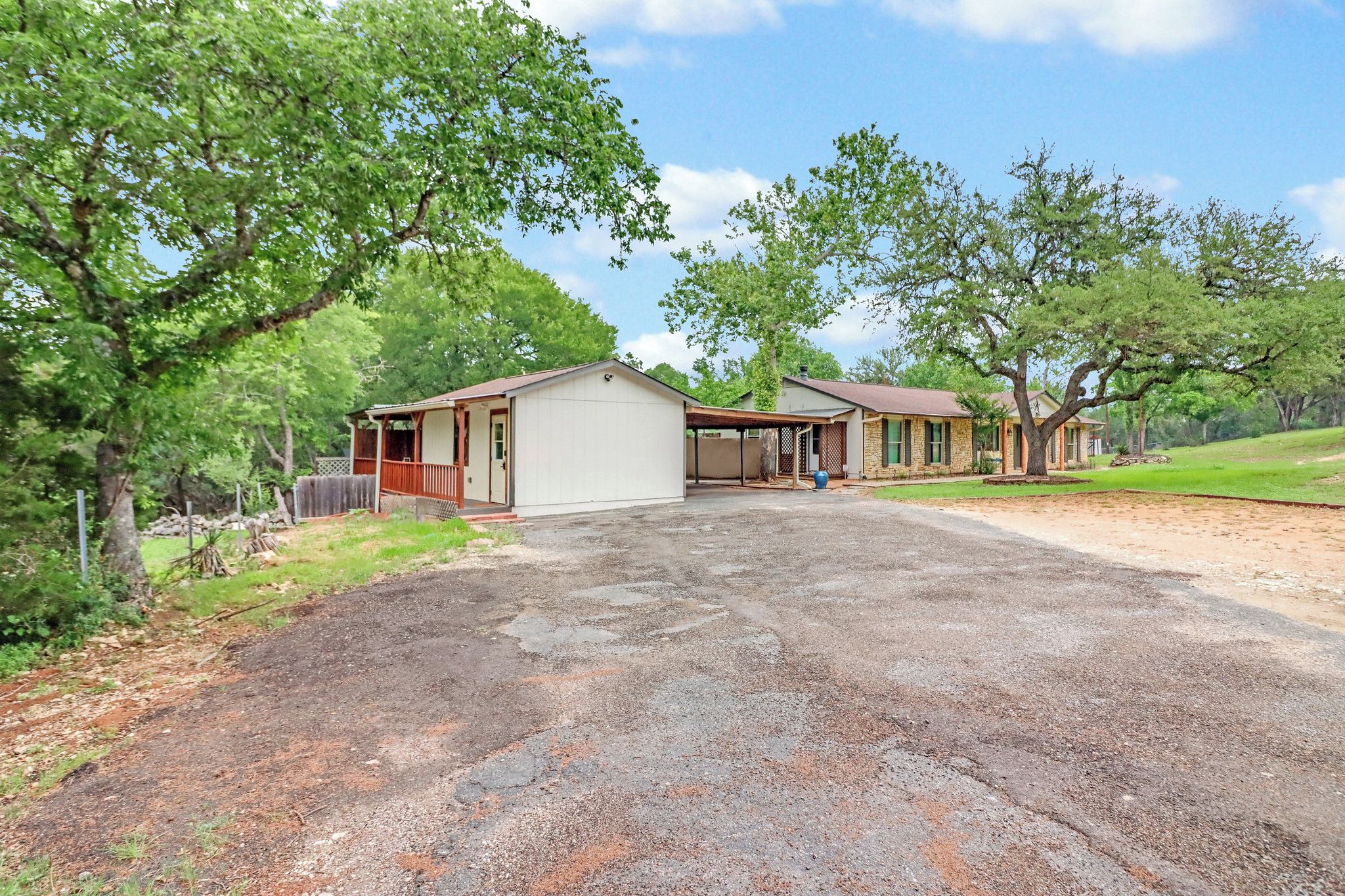 A two-story house with a covered porch, a garage, and a driveway leading to a grassy area.