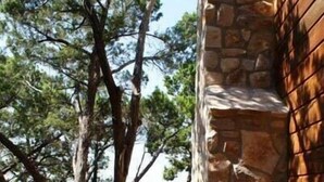 A wooden deck leading to a stone building with a view of trees and a distant landscape. - Upscale Luxury Cabin! Has it all Hot tub, Fireplace, Gorgeous Views!!! (Wimberley)