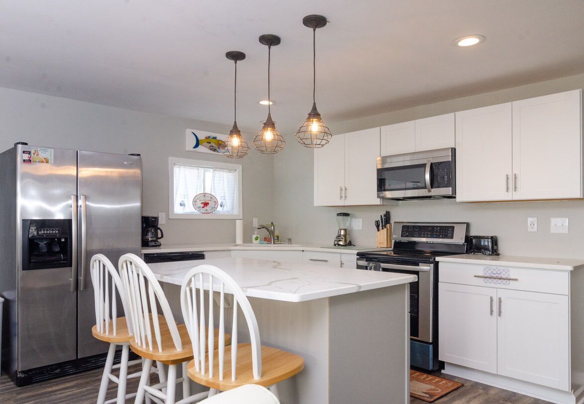 A modern kitchen with white cabinets, stainless steel appliances, and a central island with bar stools.