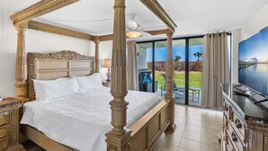 Una cama con dosel con vista a un jardín paisajista a través de una puerta corrediza de vidrio.