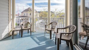 A covered porch with white columns and a view of a Ferris wheel and houses.