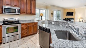 A kitchen with wooden cabinets, stainless steel appliances, granite countertops, and a built-in dishwasher.
