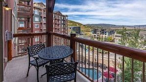 A balcony with a table and chairs, overlooking a pool and a view of a residential area with multi-story buildings. - Labor Day Sale - Limited Time Offer, Save up to 30% (Park City)