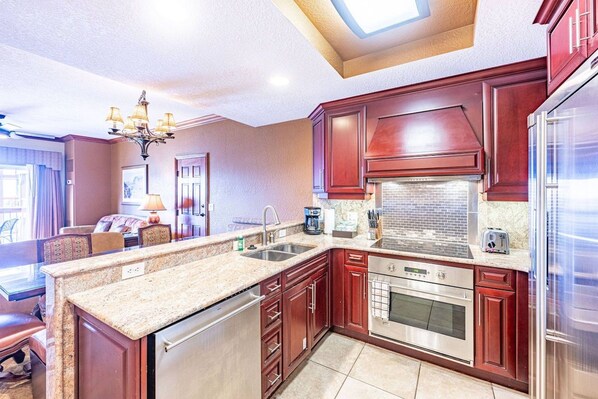A kitchen with granite countertops, stainless steel appliances, and dark wood cabinetry.