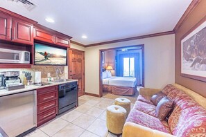 A compact living space with a kitchenette, a bed, and a sofa.