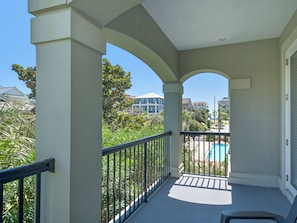 A balcony with a view of a swimming pool and surrounding houses.