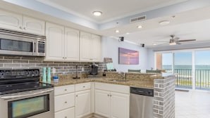 A modern kitchen with white cabinets, stainless steel appliances, and a view to the outside. - Bayfront unit in the popular Makai building (Ocean City)