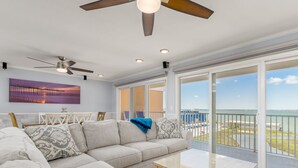 A spacious living area with a large sofa, a coffee table, and a balcony with a view of the ocean. - Bayfront unit in the popular Makai building (Ocean City)