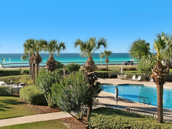 Relax by the ocean with a serene view, surrounded by lush palm trees and a pool area.