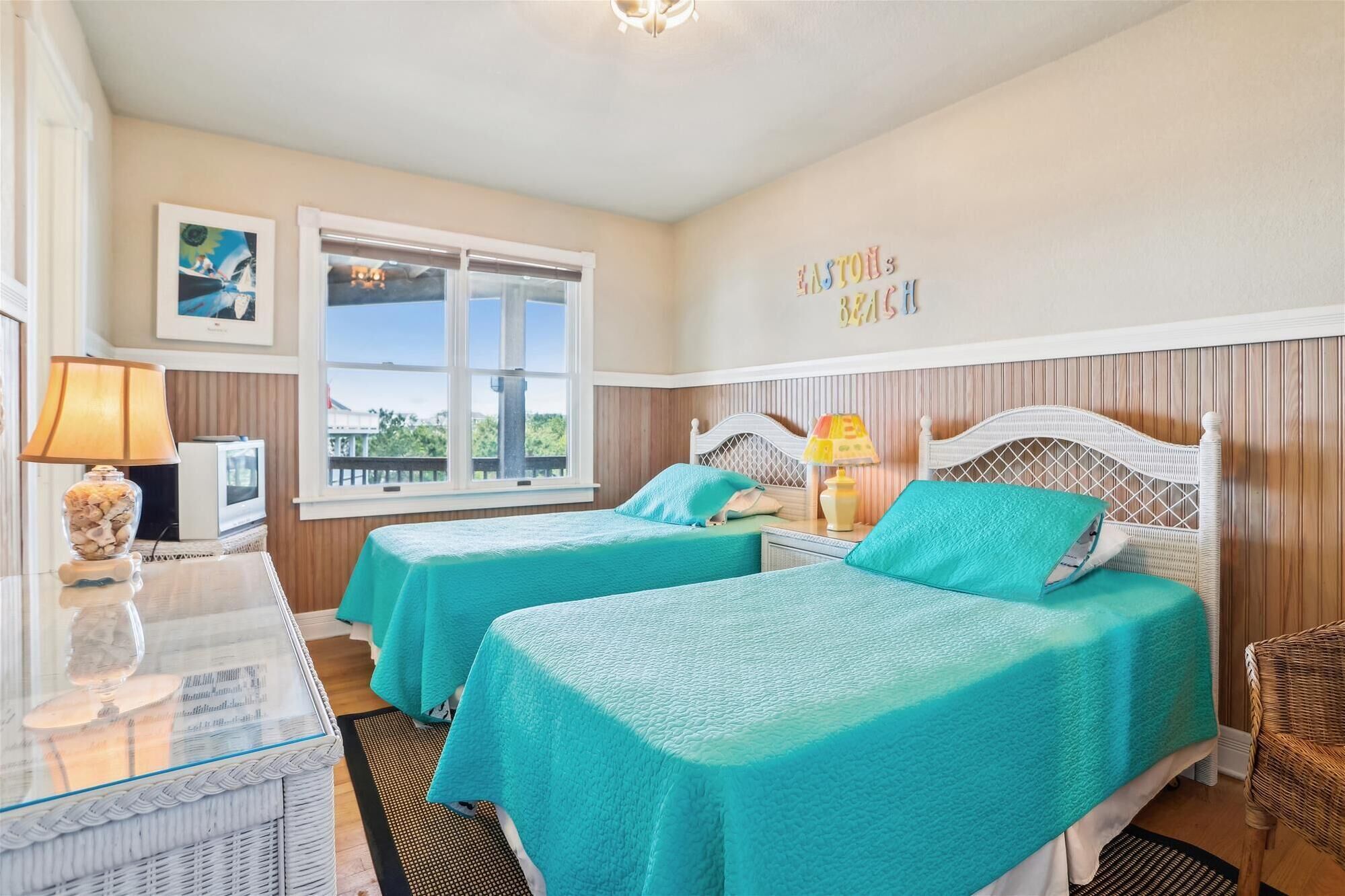 A room with two beds, a window, a lamp, and a wall with a sign.