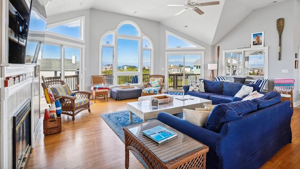 A spacious living room with a high ceiling, large windows, and a view of the ocean. - V1233- Beautiful! 5 BRs, Private Pool, Hot Tub, Pool Table and Dog Friendly! (Corolla)
