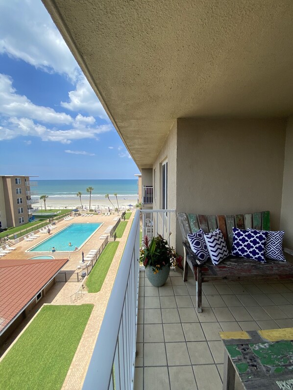 Uma varanda com vista para uma piscina, praia e oceano.