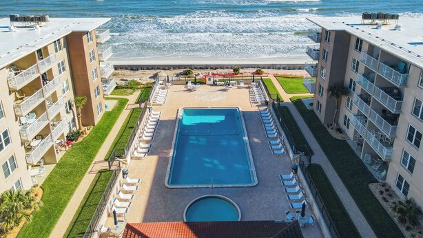 A resort with a pool, beach view, and multiple balconies. - Surfs up in this Cute 2bed/2ba condo! Ocean view! No drive Beach in NSB (New Smyrna Beach)