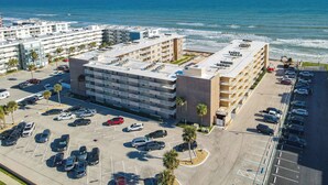 A multi-story parking structure adjacent to a beachfront hotel with a view of the ocean. - Surfs up in this Cute 2bed/2ba condo! Ocean view! No drive Beach in NSB (New Smyrna Beach)