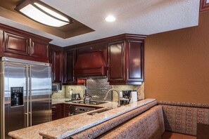 A kitchen with dark wood cabinets, stainless steel appliances, and a built-in seating area.
