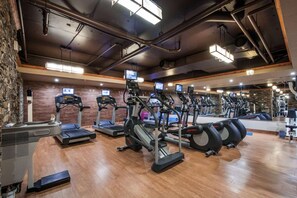 A gym with treadmills, ellipticals, and a mirror wall.