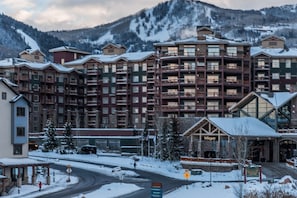 A multi-story hotel with balconies, a ski resort in the background, and a sign for 'Summit'.