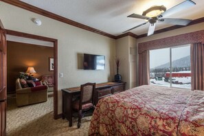 A hotel room with a bed, a desk, a chair, a television, and a large window with a view of a snowy landscape. - Westgate 4606 (Park City)