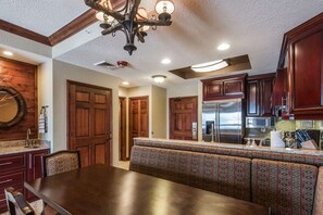 A kitchen with wooden cabinets, a built-in oven, and a seating area with patterned cushions. - Westgate 4606 (Park City)