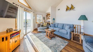 Una sala de estar moderna con un sofá, una mesa de centro y un televisor sobre un mueble de madera.
